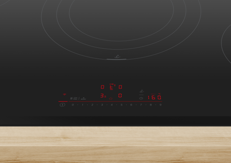 Primer plano de placa de inducción Bosch encendida sobre una encimera de madera.