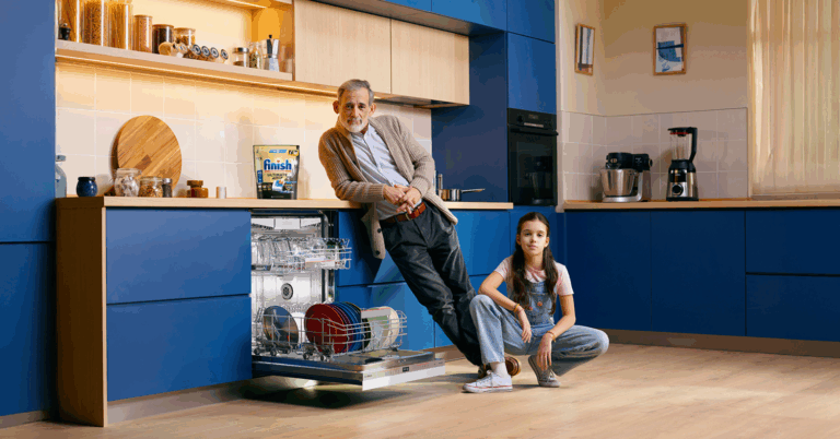 Un abuelo y su nieta en una cocina moderna azul delante de un lavavajillas Bosch abierto, y hay un paquete de Finish en la encimera