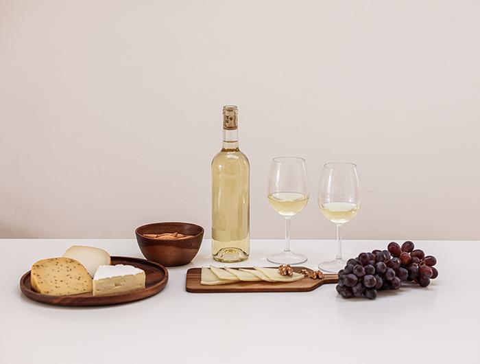 Copas de vino blanco con variedad de quesos y aperitivos