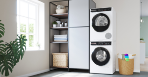 Cuarto de lavado luminoso con lavadora y secadora Bosch instaladas en columna. Junto a ellas, un armario con estantería y un cesto de ropa sucia.